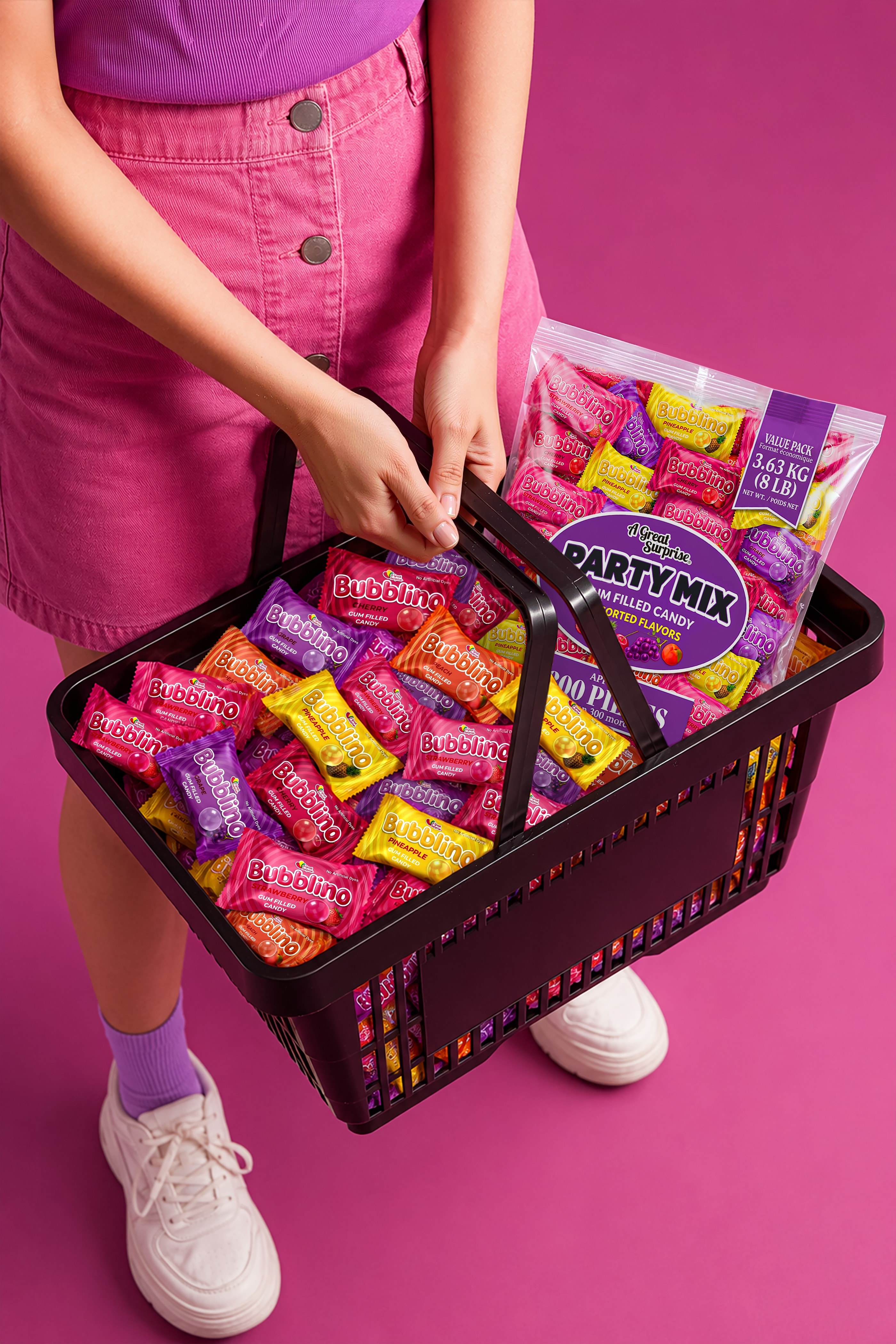 Shopper in pink on magenta carrying a black basket loaded with Party Mix packs