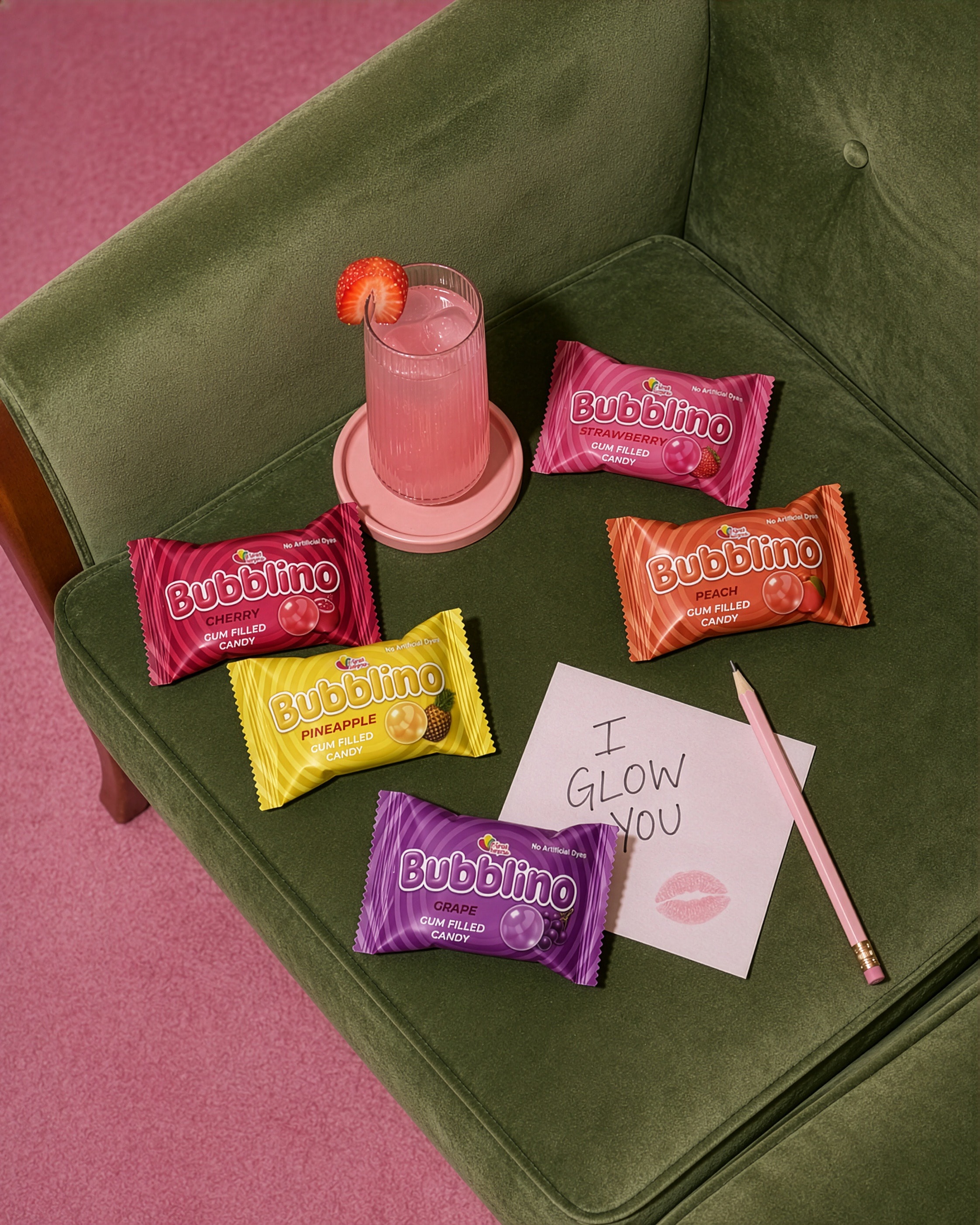 Bubblino candies scattered on a green velvet armchair beside a handwritten note reading I glow you
