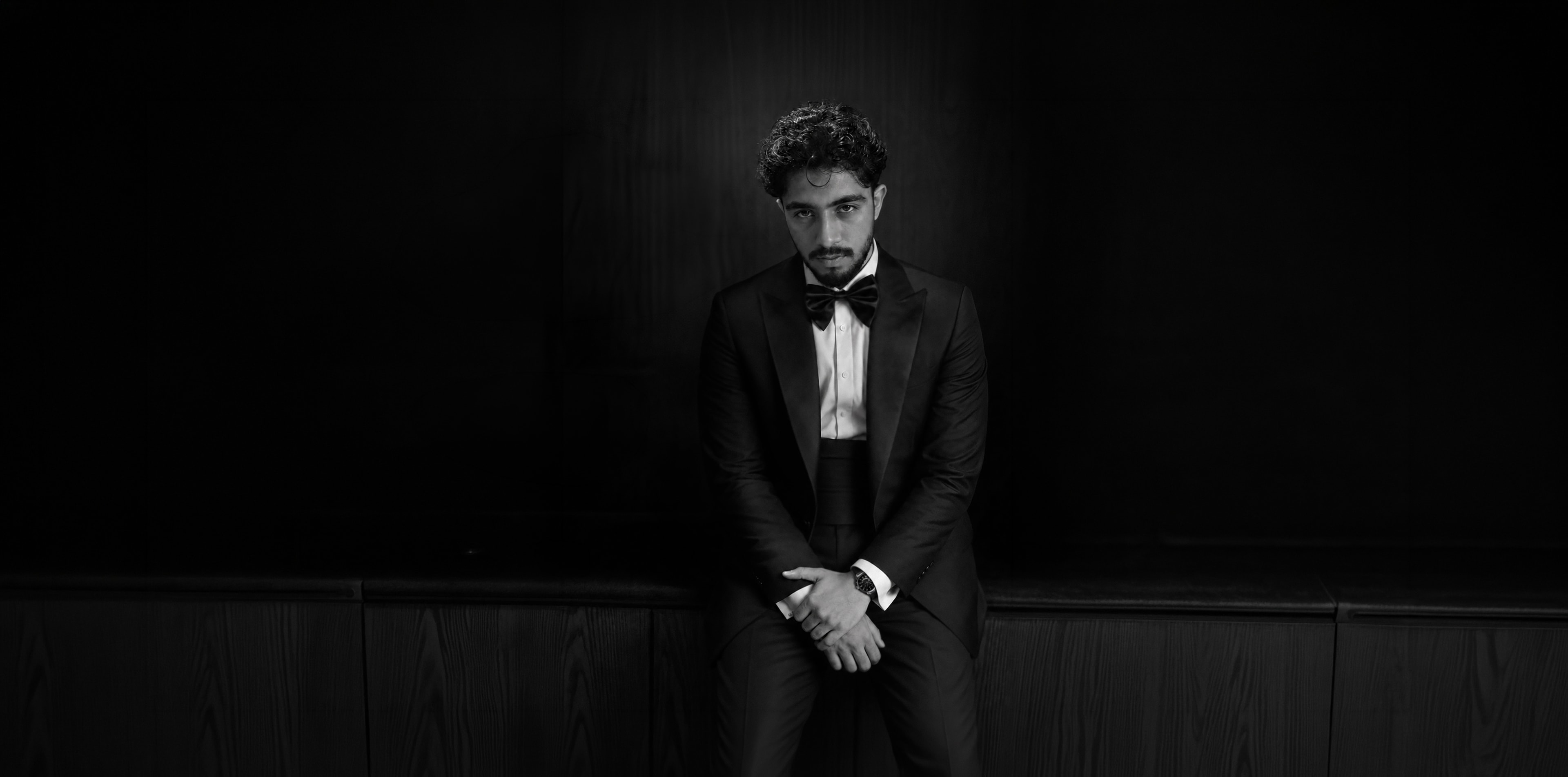 Rafsan Hossain in a black tuxedo, seated — portrait